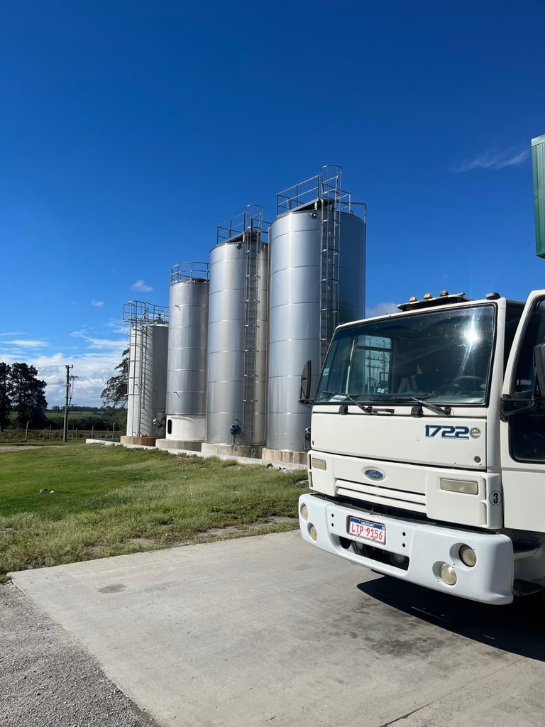 Silos de acero inoxidable y camión cisterna de recolección de leche en una planta uruguaya