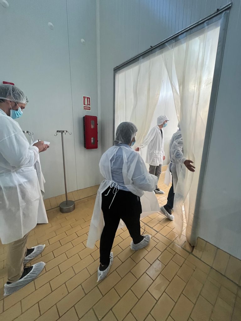 Personas con batas y cofias ingresando a un área de producción de alimentos